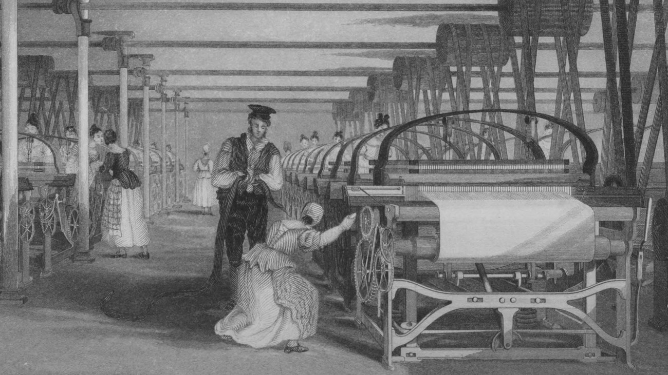 A woman weaving at a powerloom while a man supervises her